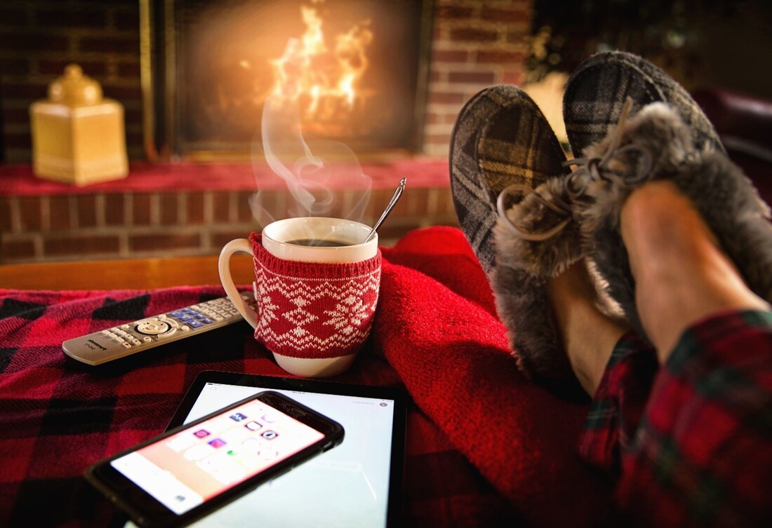 A fireplace with flickering flames, a coffee cup and feet in snuggly slippers.